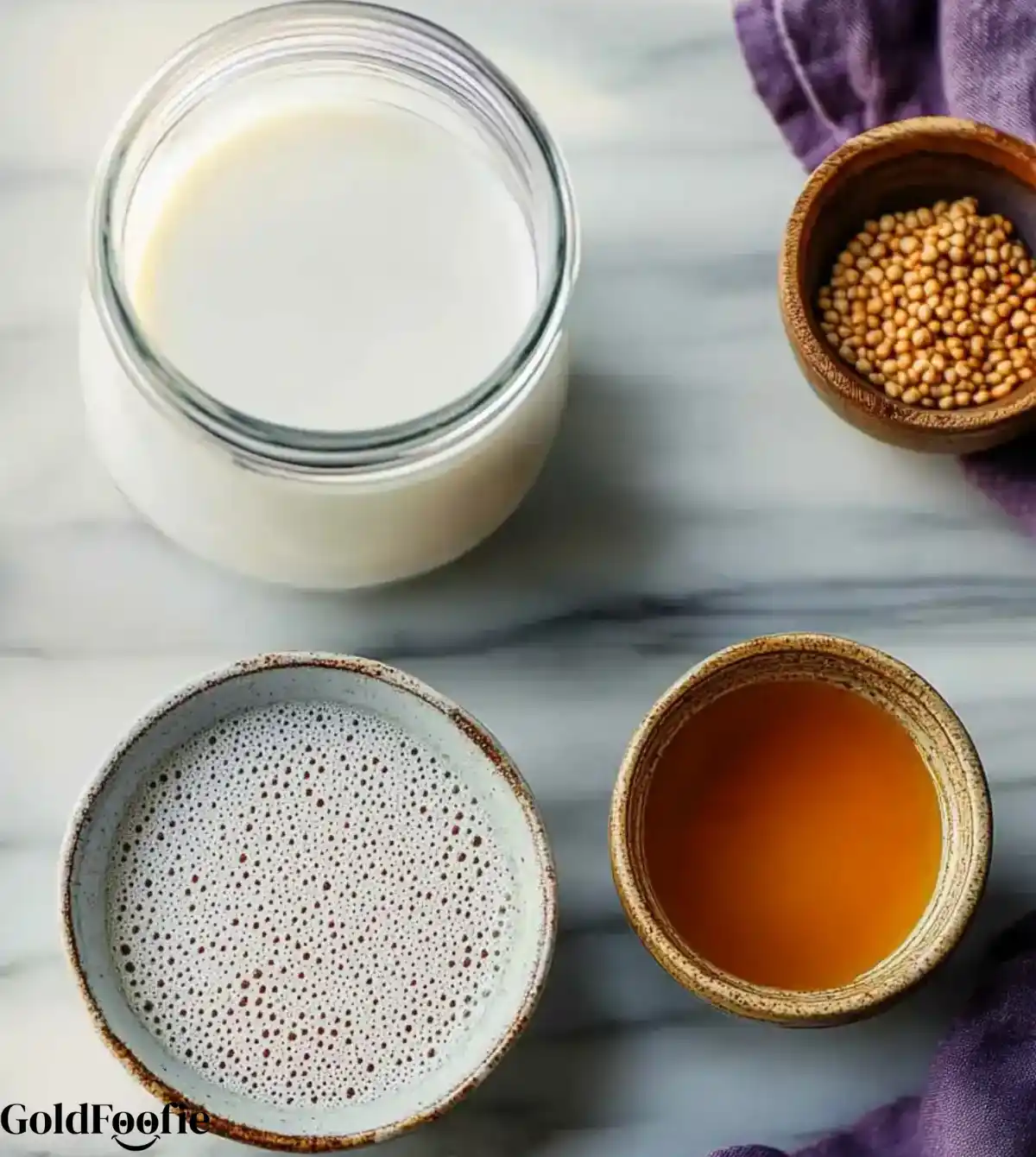 Chia_Pudding_Recipes_Ingredients Overhead view of chia seeds, plant milk, and maple syrup in ceramic bowls on a marble counter