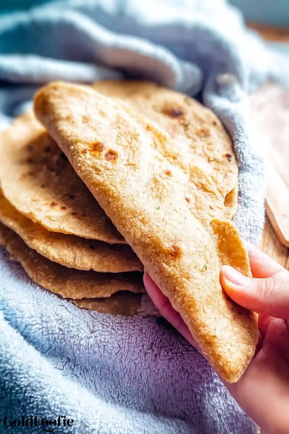 Easy Healthy Tortilla Hand picking up a soft folded healthy tortilla from a stack of homemade wraps