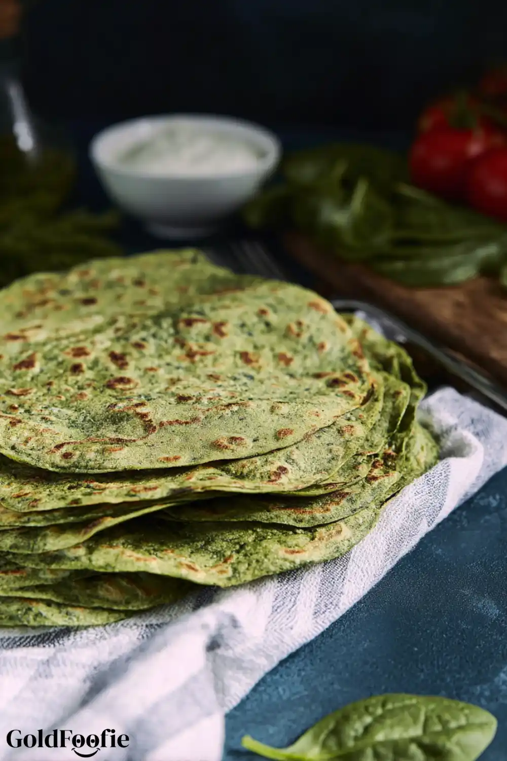 Large Batch of Homemade Spinach Tortillas Large stack of spinach tortillas on striped kitchen towel