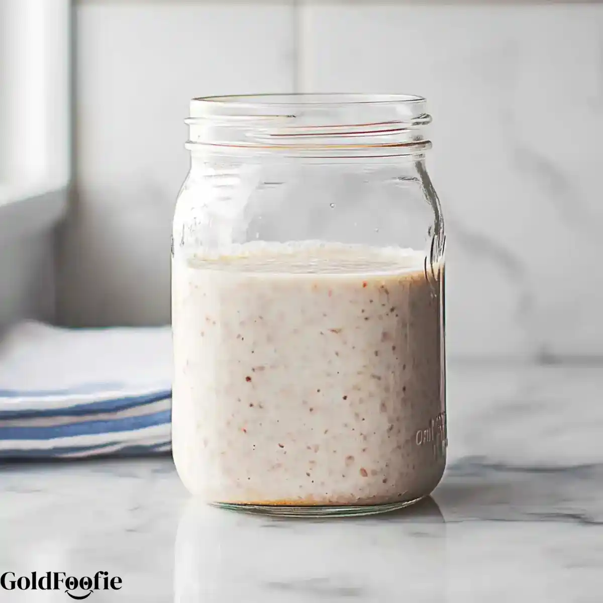 mix_chia_ingredients Mason jar filled with blended banana chia pudding on a marble counter near a striped napkin
