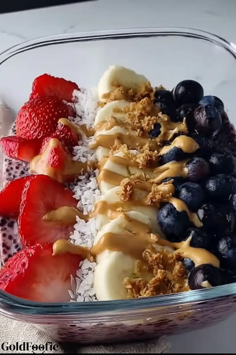 Colorful Tropical Smoothie Chia Meal Prep Jar Strawberries, banana, blueberries, coconut flakes, and granola over Tropical Smoothie Chia in a meal prep container