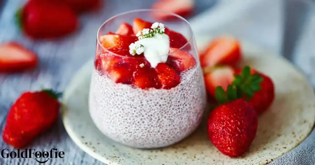Strawberry chia pudding in a glass topped with fresh berries and cream