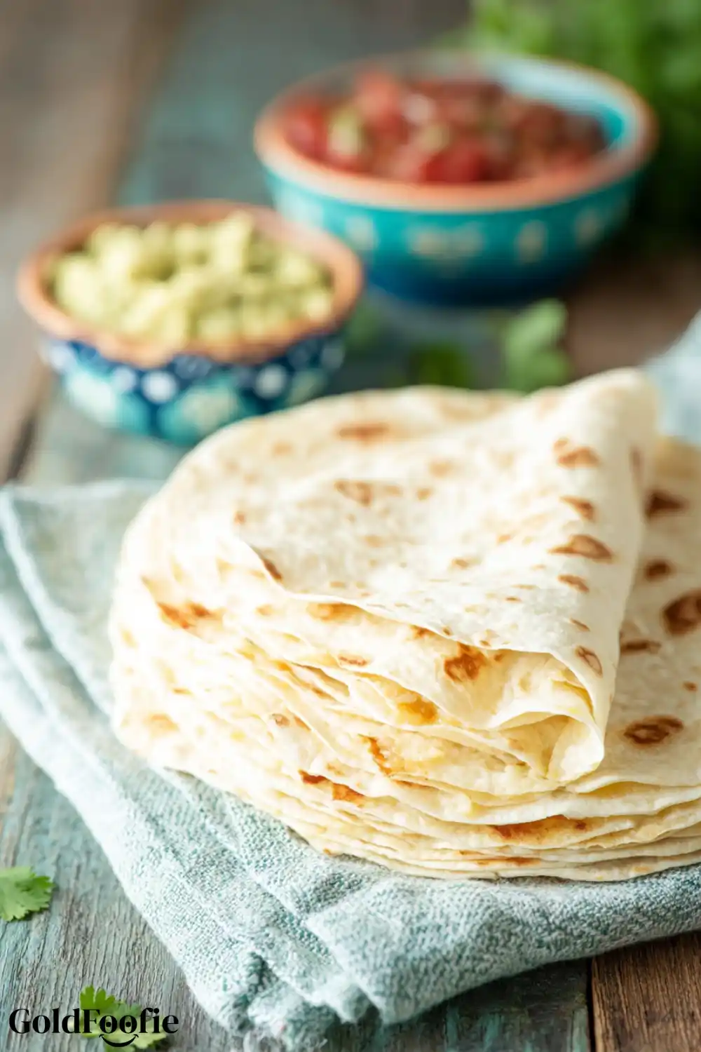 Fresh 12 Inch Flour Tortilla Stack Stack of 12 Inch Flour Tortillas with one folded on a teal towel
