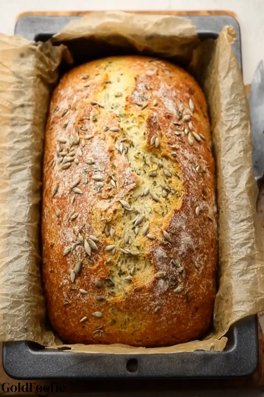 Fresh From the Oven - Diabetic bread recipes A golden-brown loaf of seeded Diabetic bread recipes resting in a loaf pan lined with parchment paper.