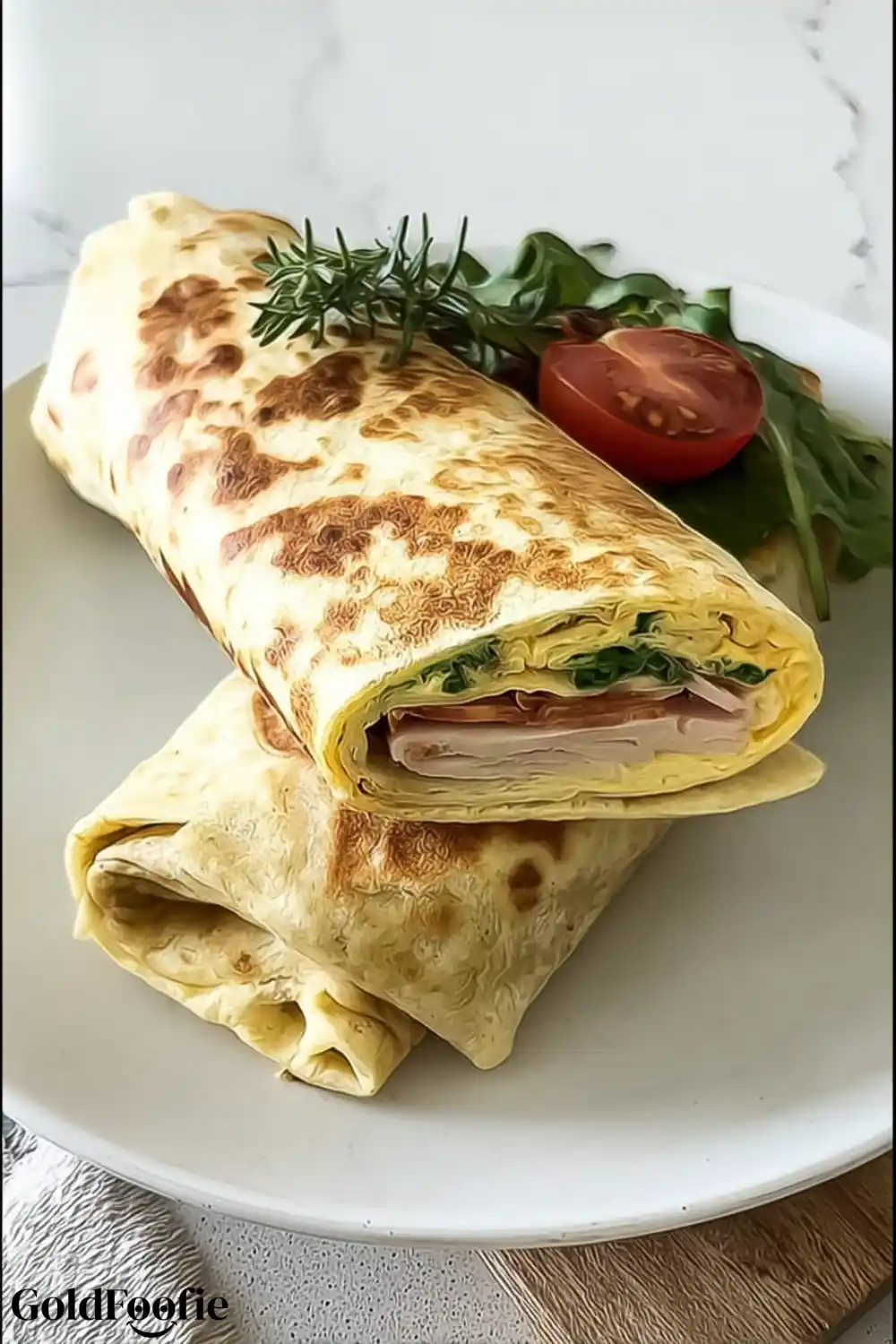 Golden Cheese-Based Wrap with Herb Garnish Cheese-based wrap rolled tightly with turkey, greens, and tomato, garnished with rosemary