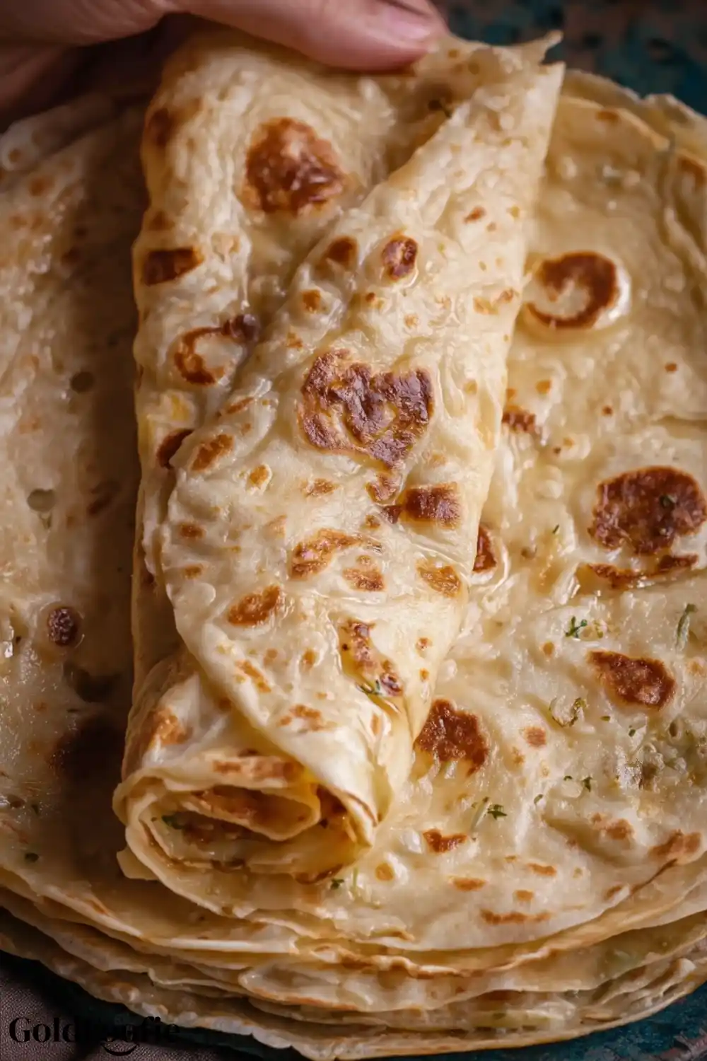 Handmade Burrito Tortilla Stack Stack of burrito tortillas with golden crusts and rolled edges in hand.