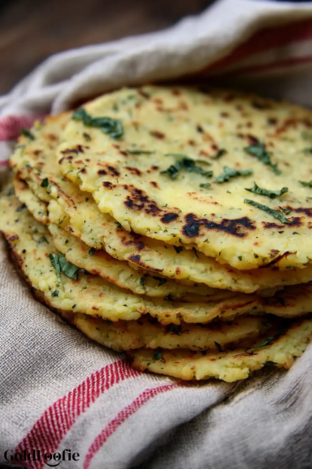 Keto-Friendly Cauliflower Tortillas for Wraps and Tacos Golden cauliflower tortillas with herb flakes stacked in a towel