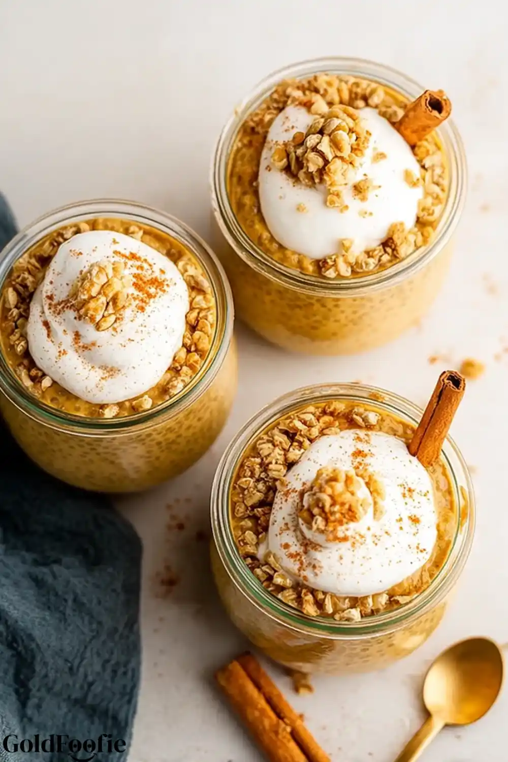 Pumpkin Chia Meal Prep Three jars of pumpkin chia pudding topped with whipped cream and granola.