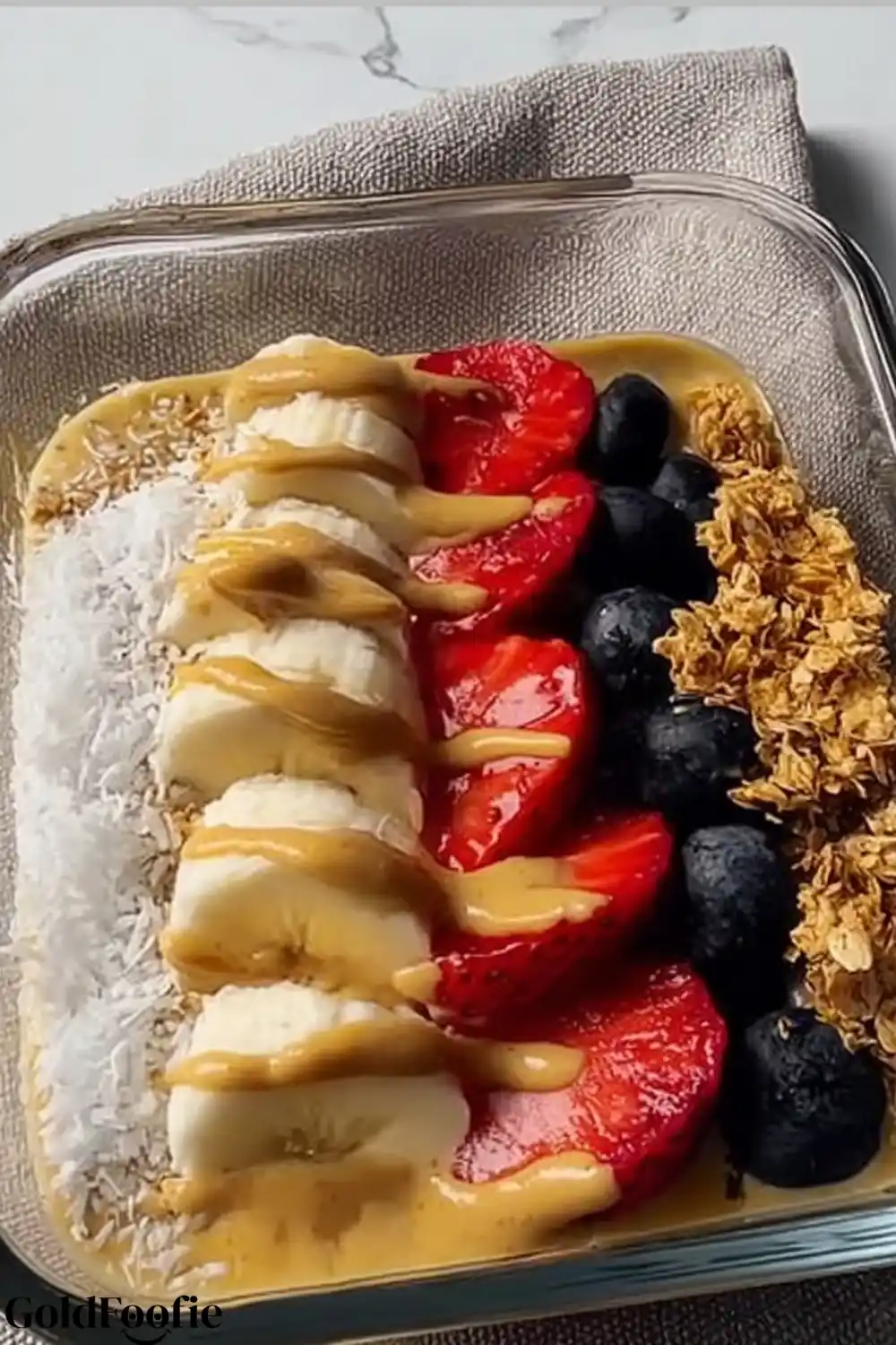 Tropical Smoothie Chia Bowl with Banana and Coconut Tropical Smoothie Chia with banana, strawberries, coconut, granola, and peanut butter drizzle on a neutral napkin