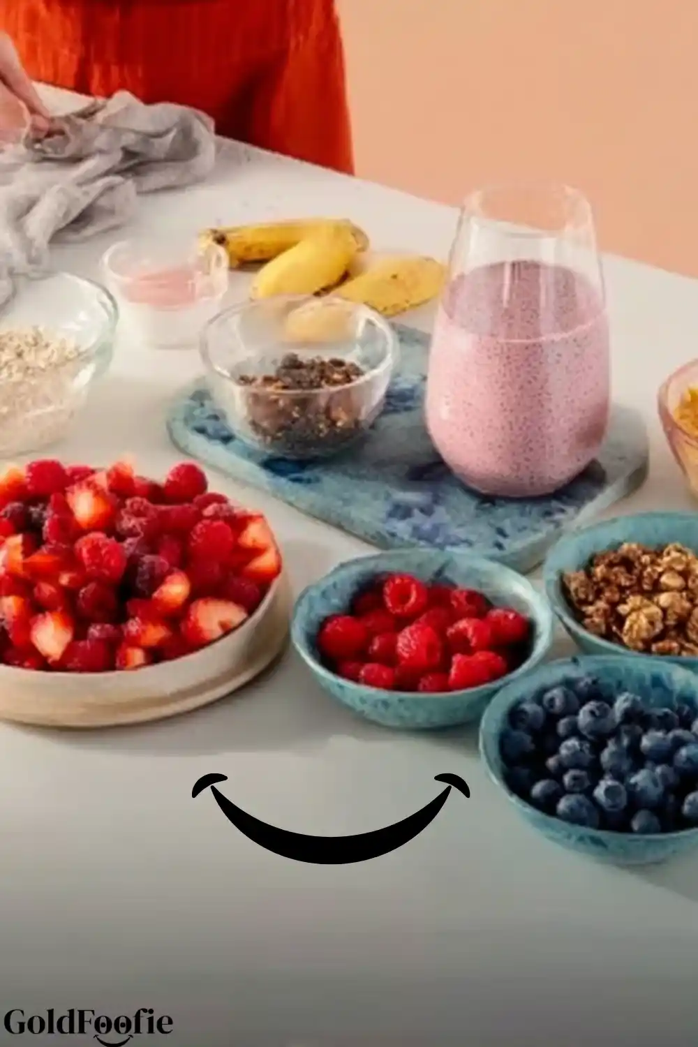 Tropical Smoothie Chia Ingredients and Prep Setup Ingredients for Tropical Smoothie Chia recipe including berries, oats, bananas, chia pudding, and granola on a countertop