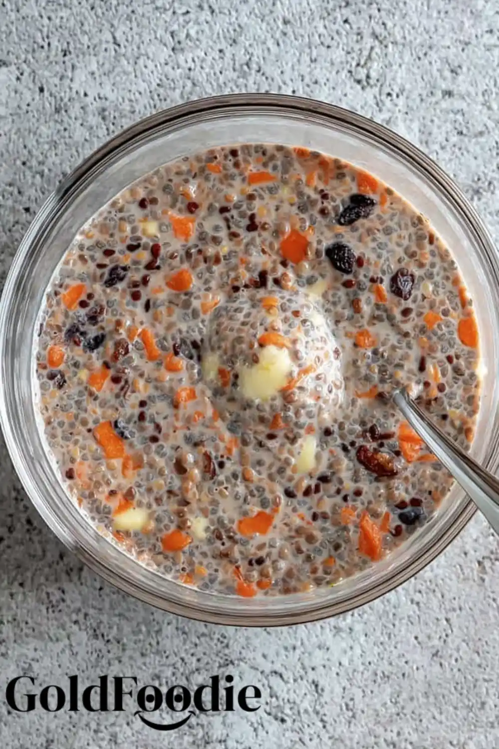 Chia Mix with Carrots Overhead view of carrot cake chia pudding mixture in a clear bowl with visible carrot and raisins.