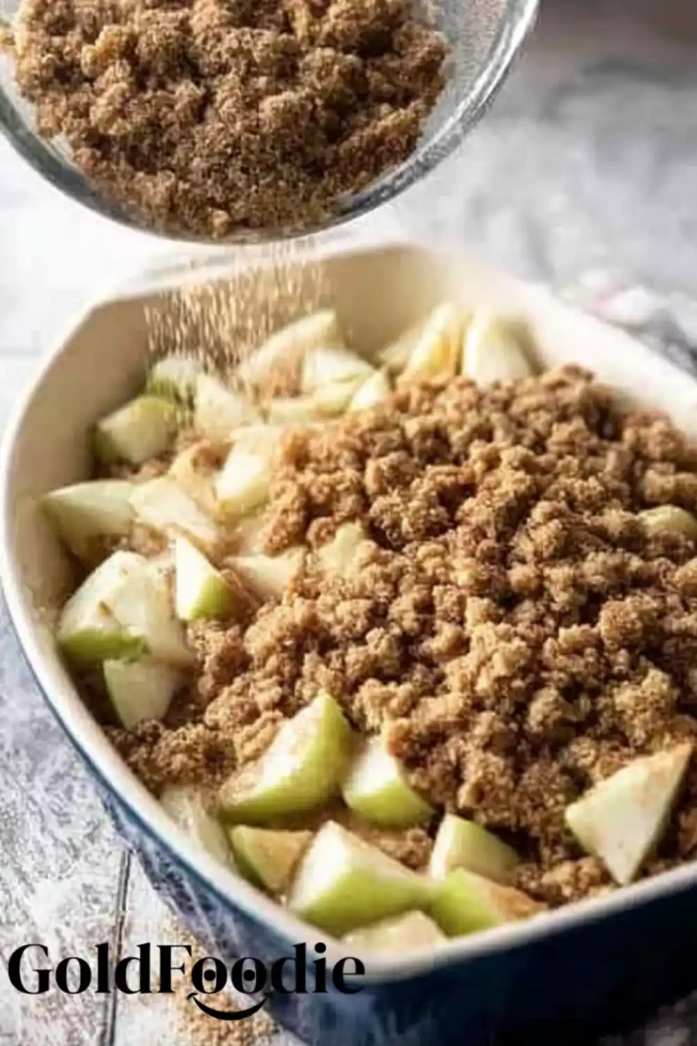 Crumble Topping Assembly Topping mixture being added to apples in dish