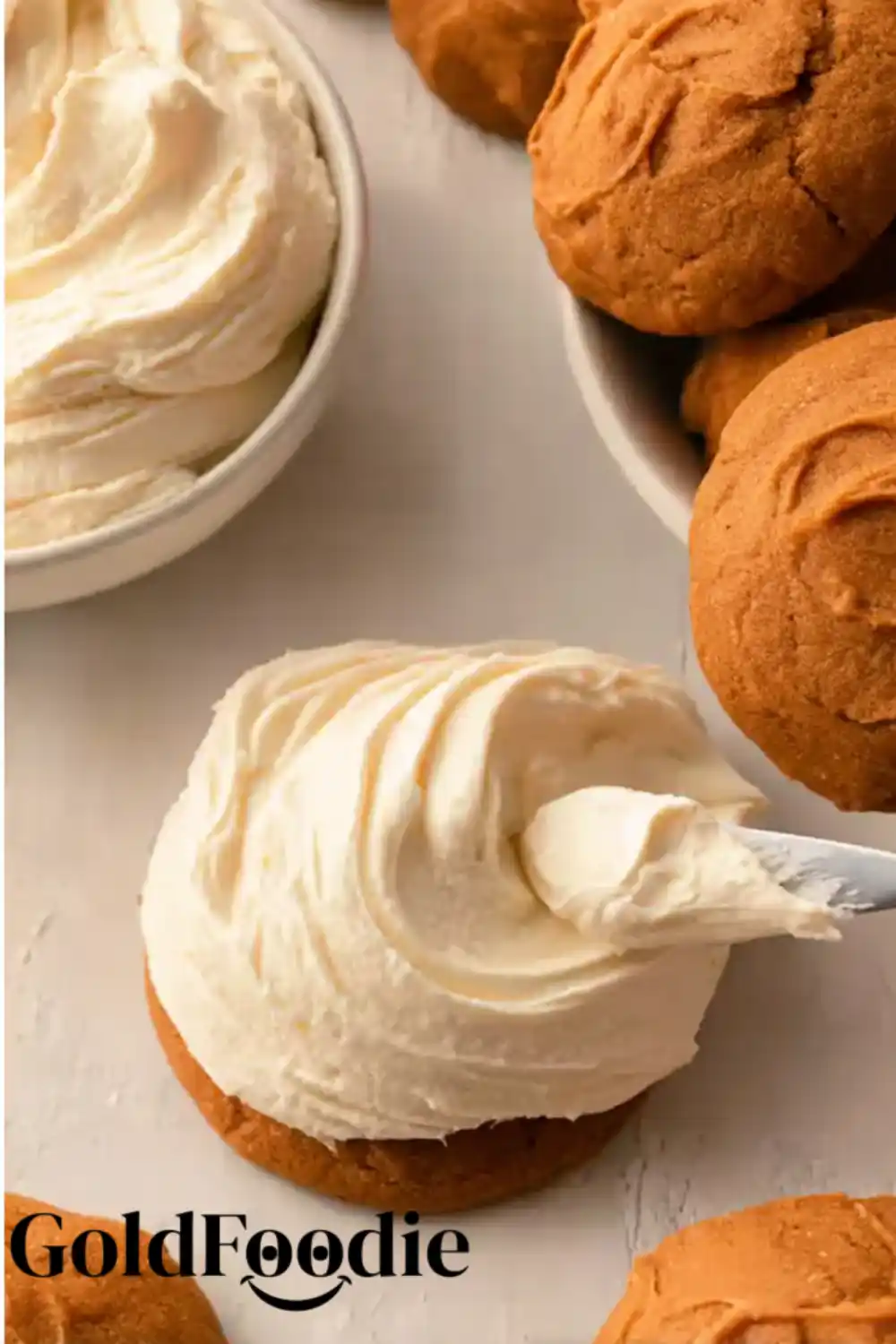 Frosting Pumpkin Cookies Spreading cream cheese frosting on pumpkin cookie