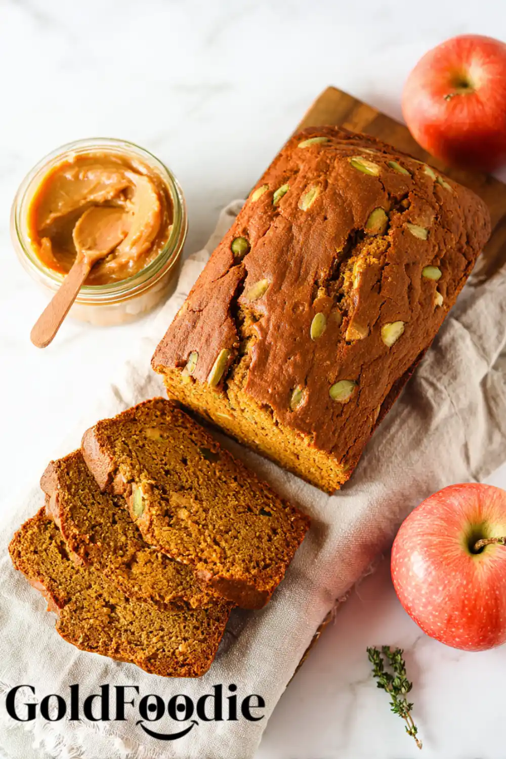 Gluten-Free Pumpkin Apple Bread An overhead shot of a sliced pumpkin apple bread topped with pumpkin seeds, with apples and apple butter nearby.