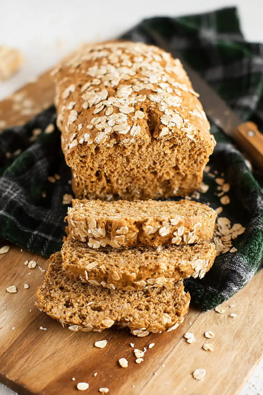 Healthy Vegan Oat Bread Oat bread loaf cut in slices over a plaid towel.