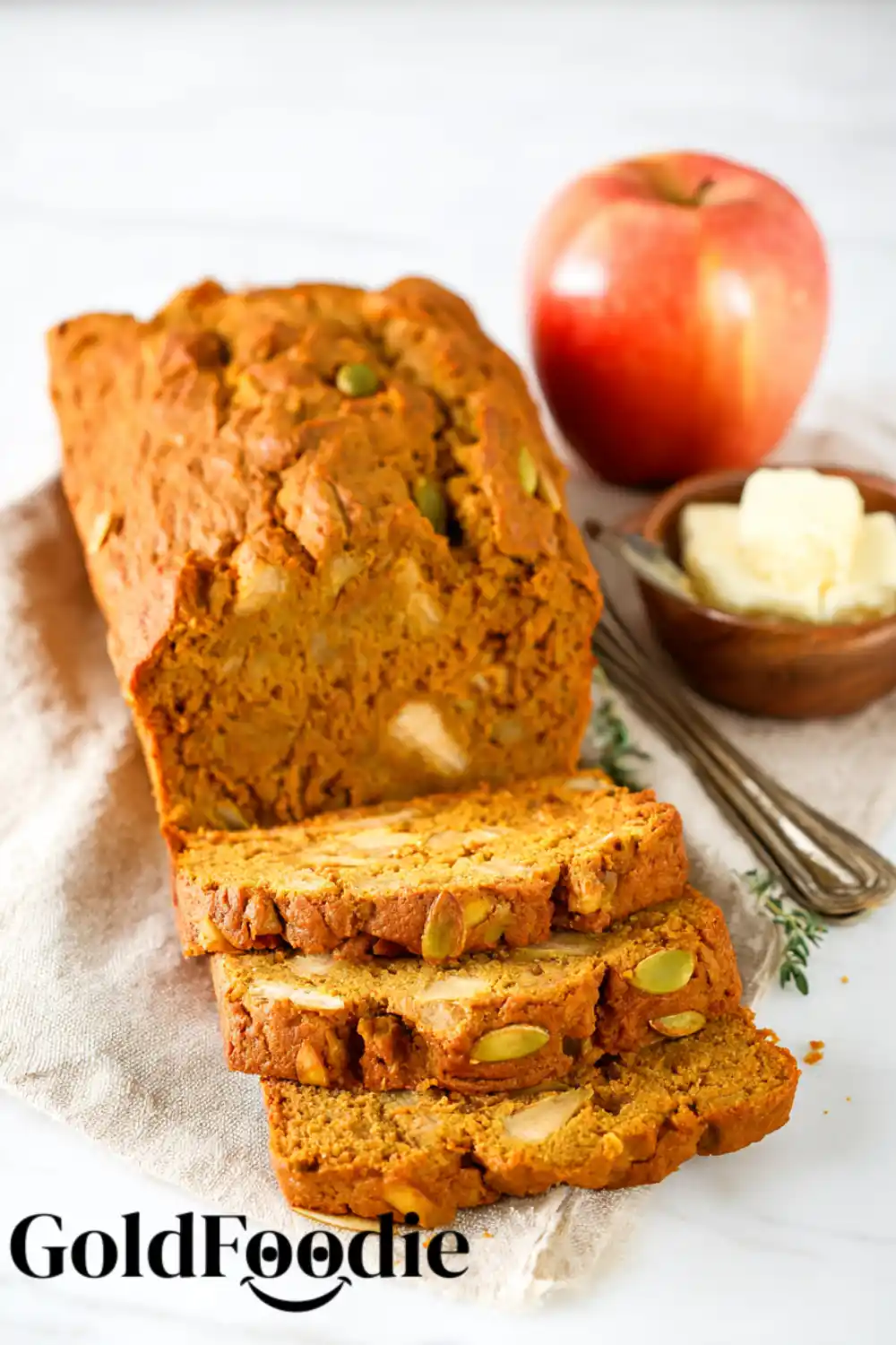 Vegan Pumpkin Apple Bread Slices Three thick slices of pumpkin apple bread in front of the main loaf, with a side of butter.